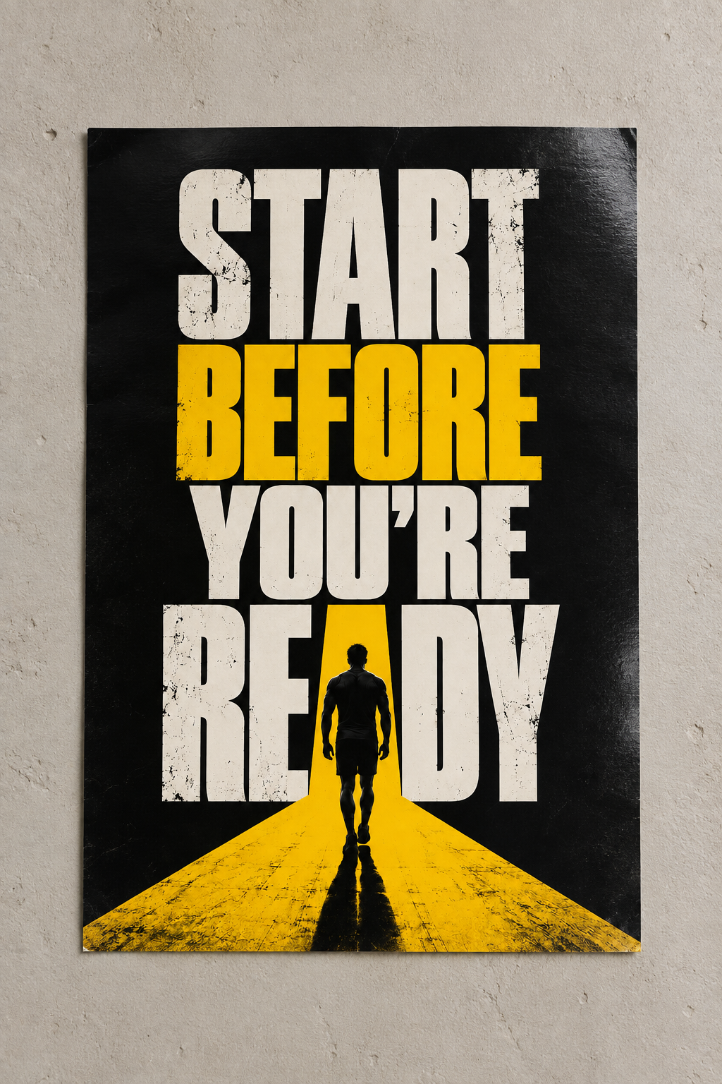 Bold START BEFORE YOU'RE READY lettering in white and yellow with a silhouette walking down a yellow road, poster on a plain wall