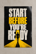 Bold START BEFORE YOU'RE READY lettering in white and yellow with a silhouette walking down a yellow road, poster on a plain wall