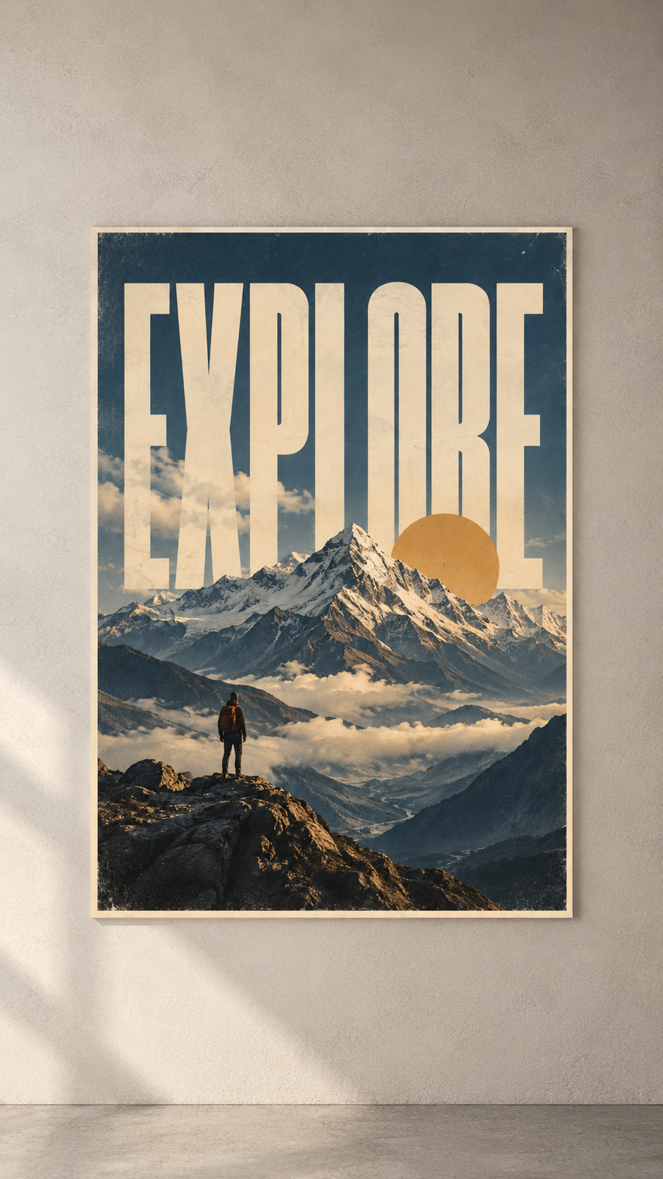 A lone hiker on a rocky peak above snowy mountains and clouds, under EXPLORE lettering and a gold sun, poster on a plain wall